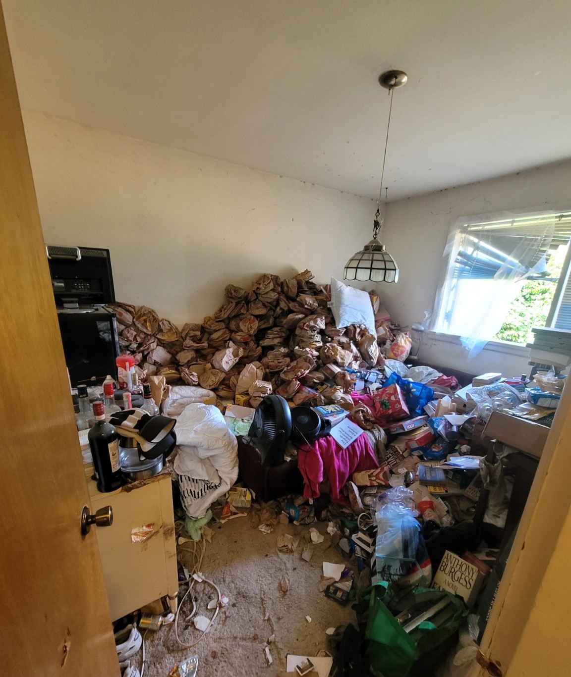 Bedroom in Departure Bay, Nanaimo buried in bags and debris before a Junk Matters hoarding cleanout