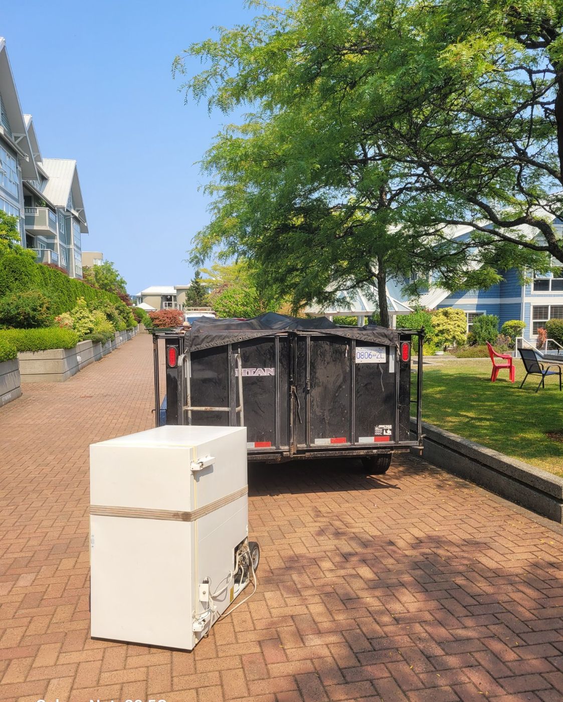A large chest freezer on a Nanaimo driveway beside the Junk Matters trailer, ready to be loaded
