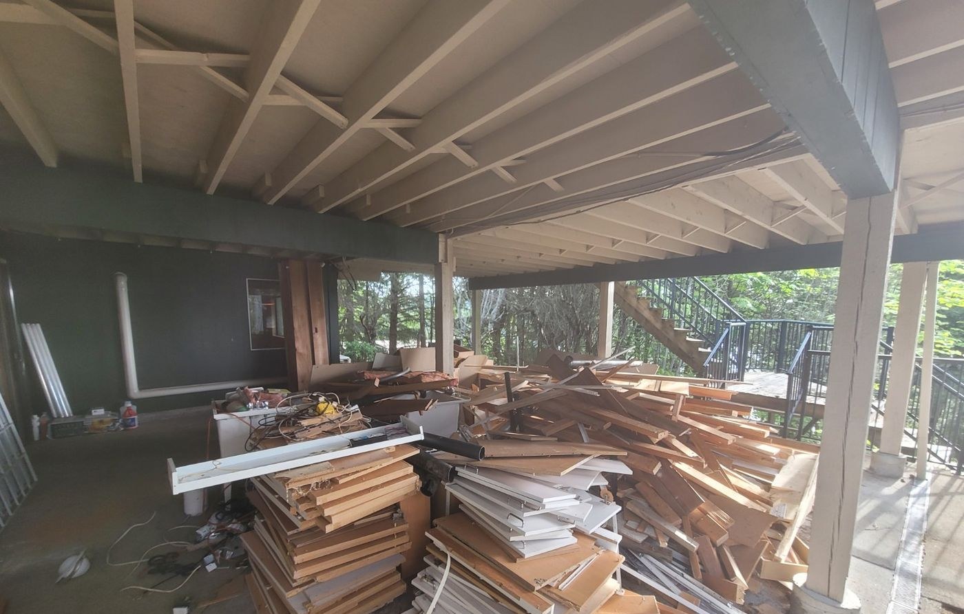 Stacks of framing lumber and torn-out building material piled under a carport after a Nanaimo renovation