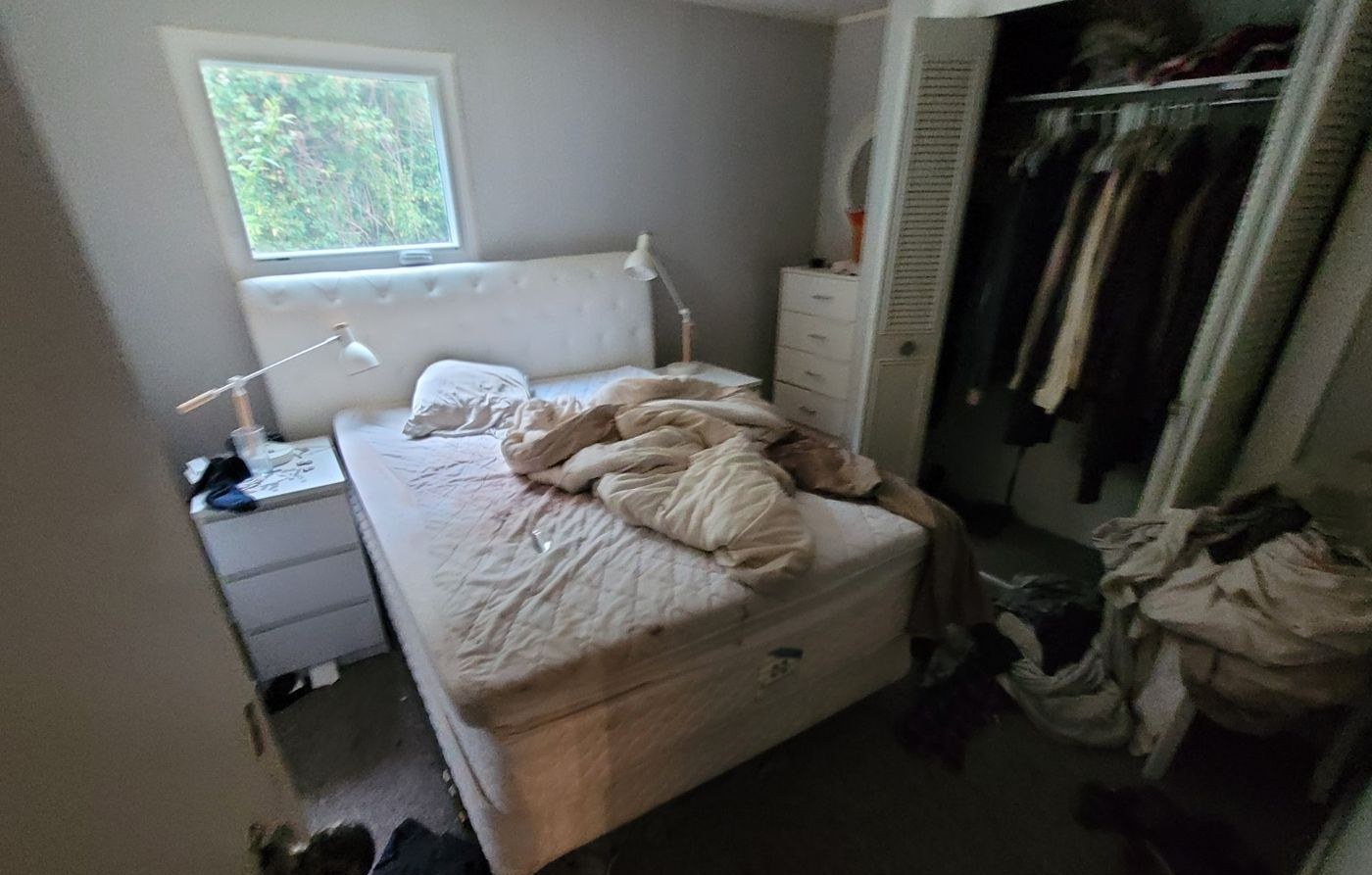 A Nanaimo bedroom with a stripped bed, open wardrobe and packed belongings during an estate cleanout