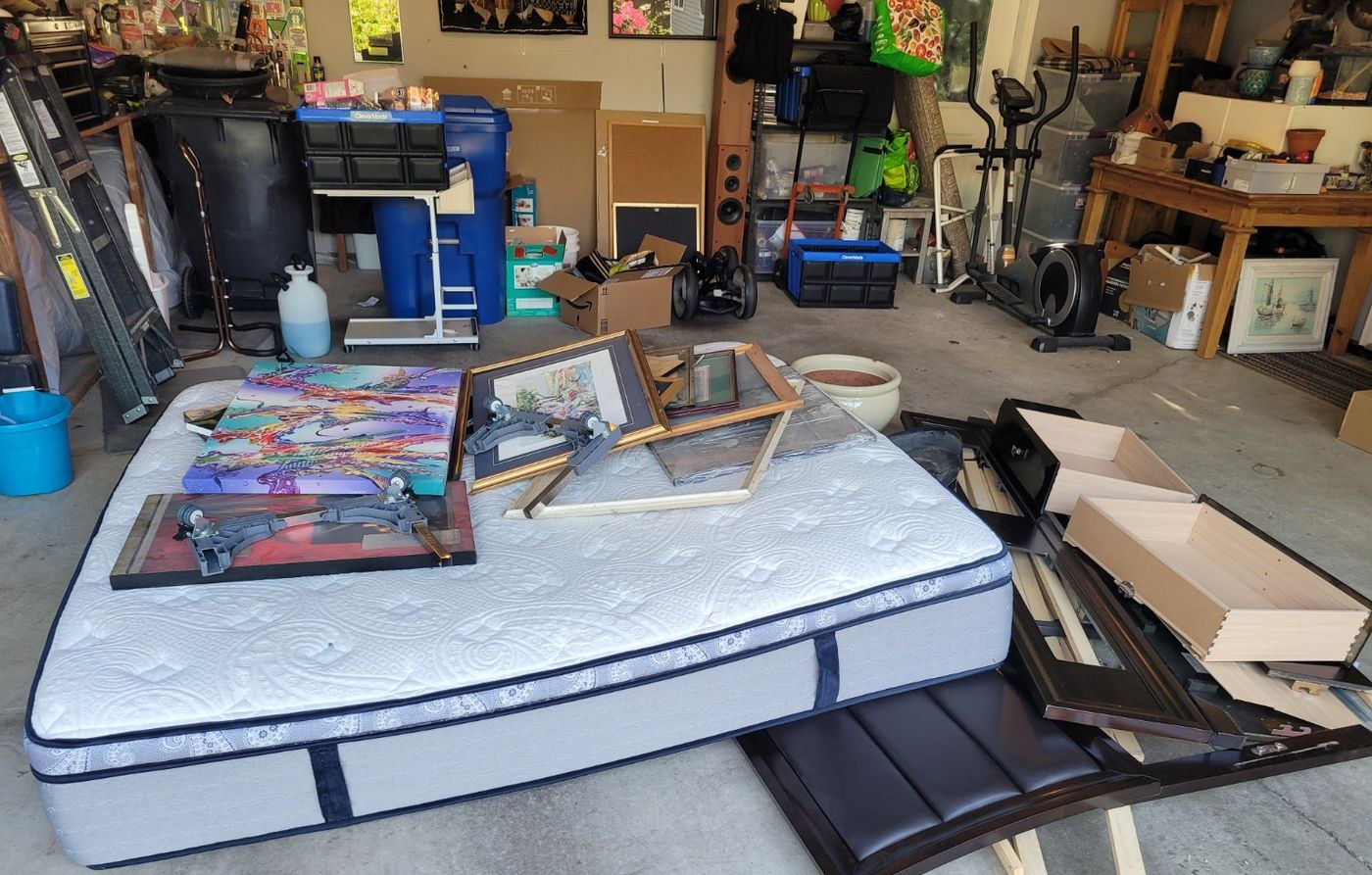 A garage filled with a mattress, framed art, exercise equipment and stored boxes before a Nanaimo cleanout