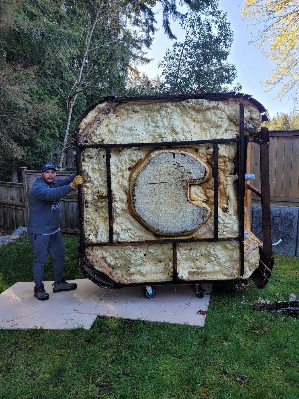 A Junk Matters crew member holding up the stripped shell of a dismantled hot tub in a Nanaimo back yard