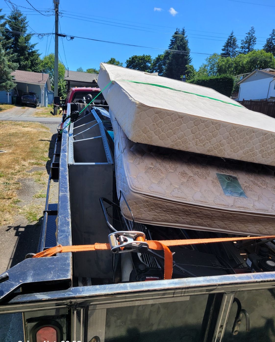 A Junk Matters trailer stacked with several mattresses and box springs strapped down for transport in Nanaimo