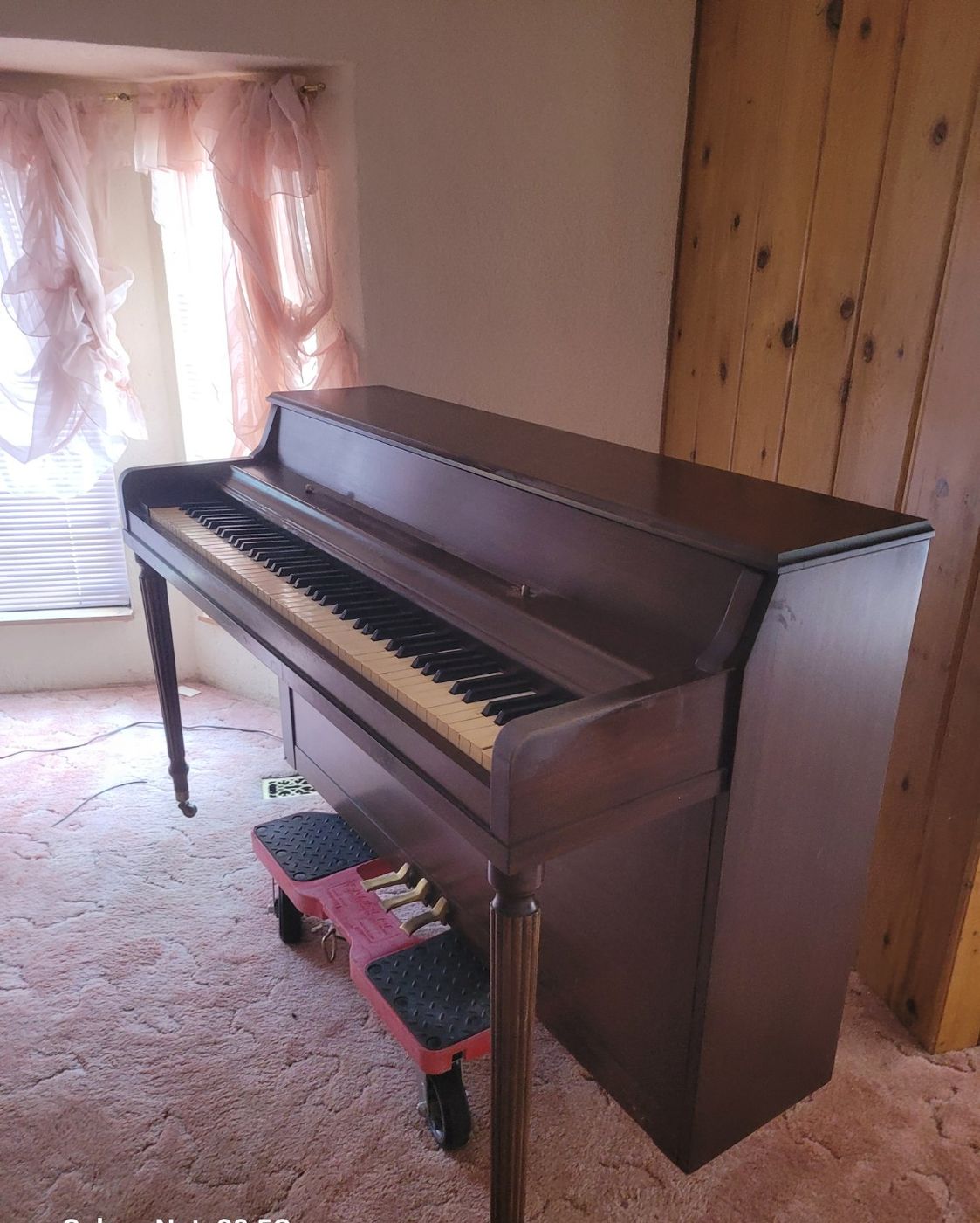 A dark wood upright piano with its bench standing against a wall in a Nanaimo home before Junk Matters removed it