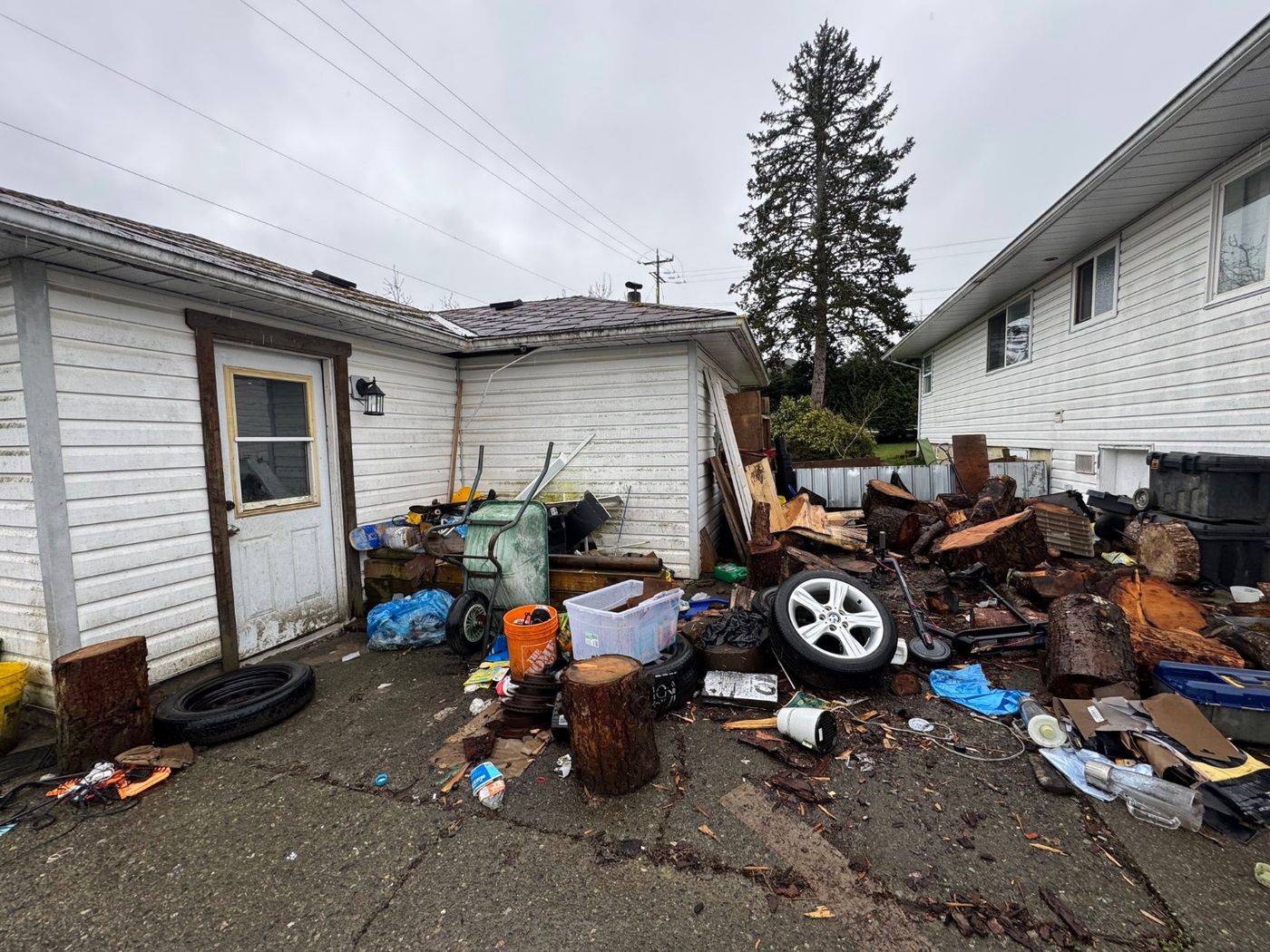 A property yard strewn with tires, timber, furniture and scattered debris before a Junk Matters cleanout in Nanaimo